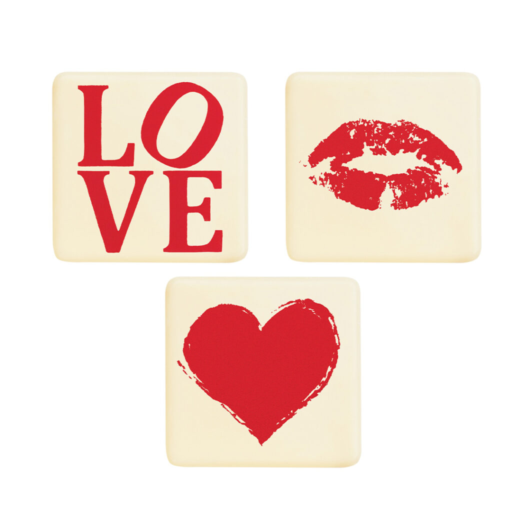 Zestaw trzech białych płytek czekoladowych na Walentynki z czerwonymi nadrukami: "LOVE", ustami i sercem.